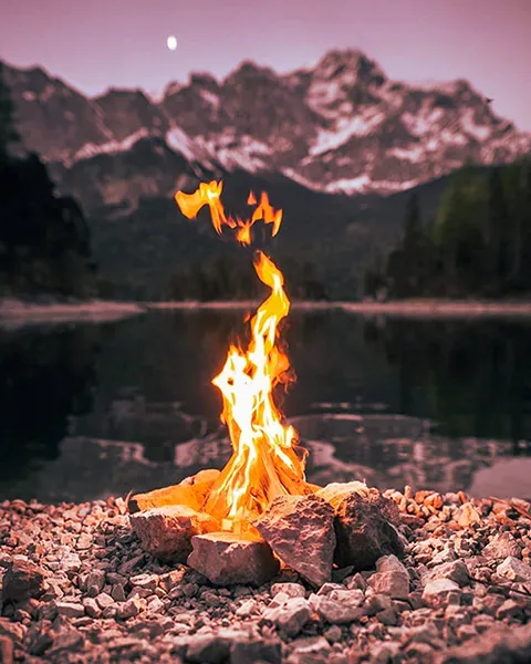 Chemin du Feu - la flamme d'un feu de camp qui s'élève devant un lac et une montagne